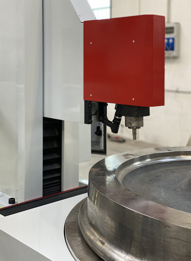 Industrial CNC machine in operation, close-up of red tool head working on metal part.