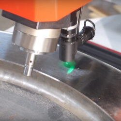 Laser engraving metal surface with precision machinery and green laser light.