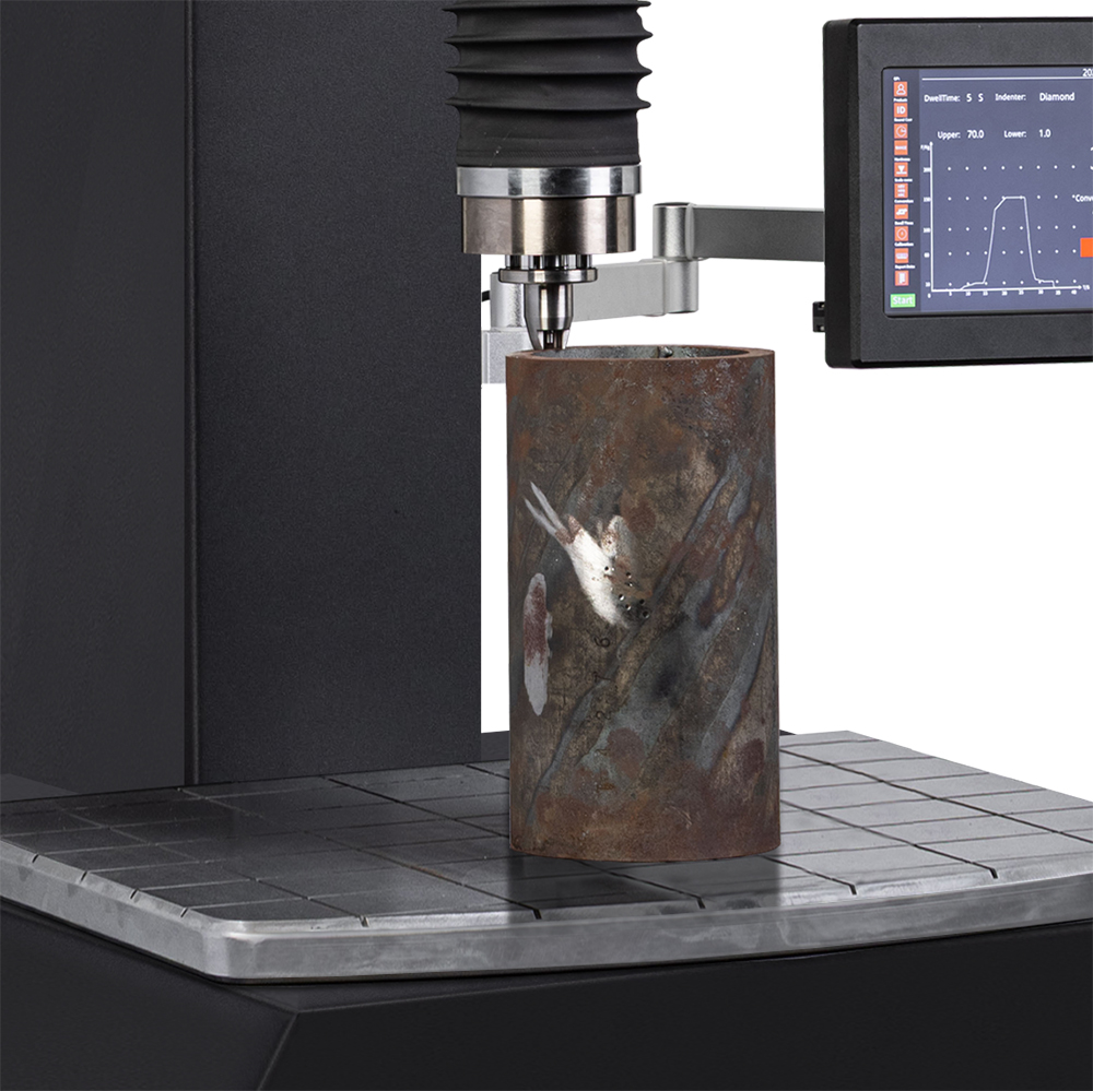 Hardness testing machine analyzing a cylindrical metal sample with a digital display.
