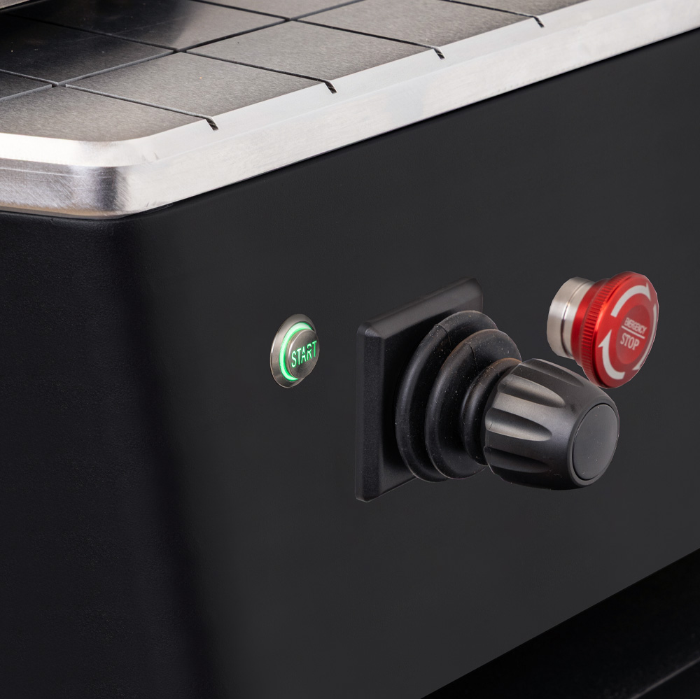 Close-up of a machine control panel with a start button and emergency stop switch.