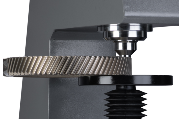 Close-up of a gear under a hardness testing machine, showcasing precision engineering.