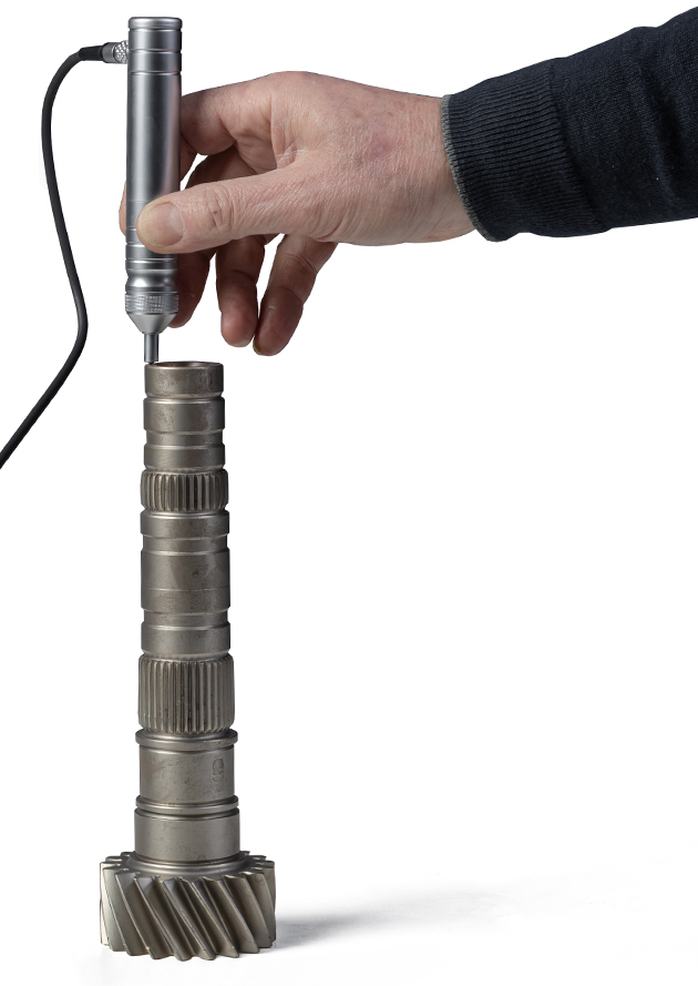 Hand measuring camshaft gear with precision tool on white background.