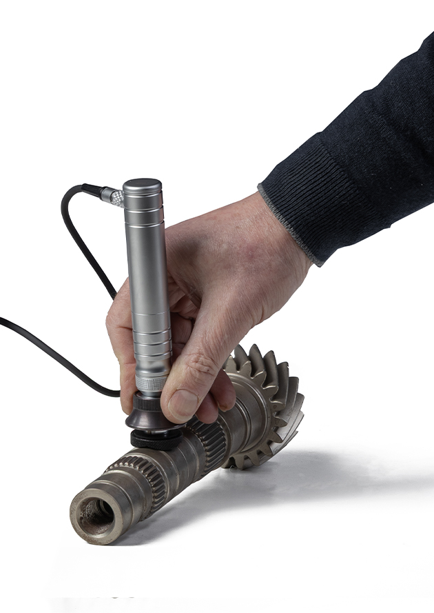 Hand inspecting gear with a precision measurement tool for quality control.