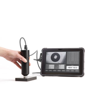 Hand using a digital hardness tester connected to a screen displaying HBW 150.9 measurement.