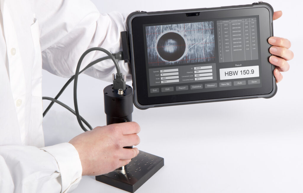 Person operating a hardness testing machine with digital display showing results.