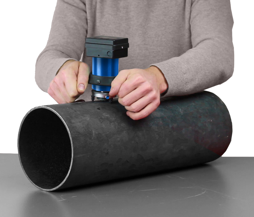 Person using a drill on a large black tube, demonstrating pipe work or machining skills.