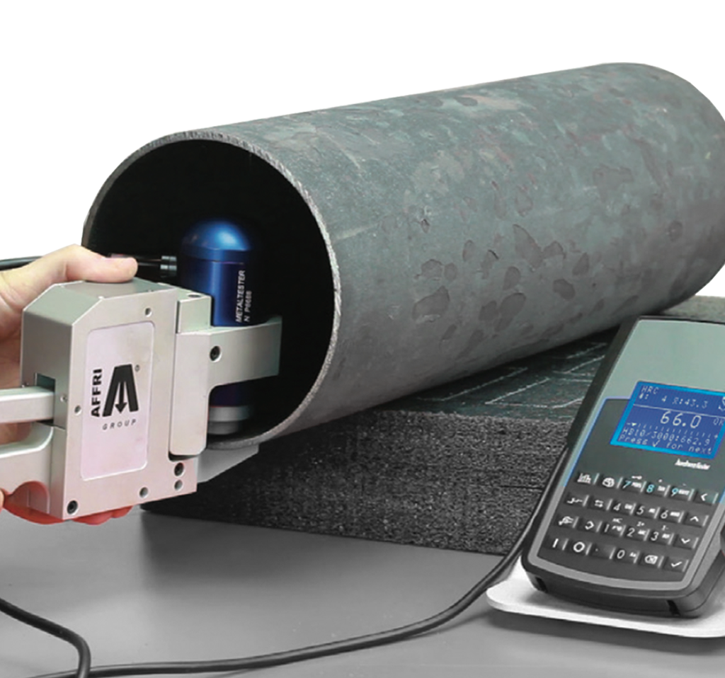 Device measuring metal pipe hardness with handheld analyzer and digital display.