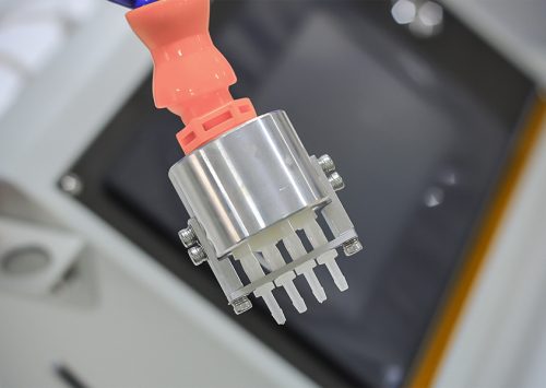 Close-up of a robotic arm gripper with metal and plastic components in a manufacturing setting.